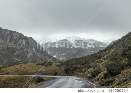 Asphalt road winding through highland mountains with clouds in the sky 112500534