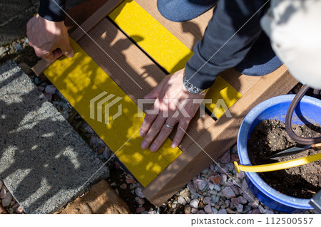 A man attaching anti-slip to a wooden deck sloop A man attaching anti-slip to a wooden deck sloop 112500557