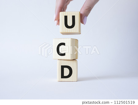 UCD - User Centered Design. Wooden cubes with word UCD. Businessman hand. Beautiful white background. Business and User Centered Design concept. Copy space. 112501519