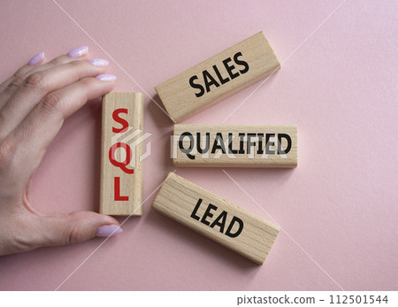 SQL - Sales Qualified Lead. Wooden cubes with words SQL. Businessman hand. Beautiful pink background. Business and SQL concept. Copy space. 112501544