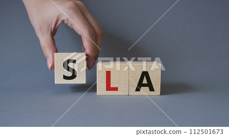 SLA - Service Level Agreement. Wooden cubes with word SLA. Businessman hand. Beautiful grey background. Business and Service Level Agreement concept. Copy space. 112501673