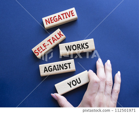 Negative self-talk works against you symbol. Concept words Negative self-talk works against you on wooden blocks. Beautiful deep blue background. Businessman hand. Psychological concept. Copy space Negative self-talk works against you symbol. Concept words Negative self-talk works against you on wooden blocks. Beautiful deep blue background. Businessman hand. Psychological concept. Copy space 112501971