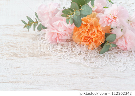 白色木質背景上的粉紅色和橙色康乃馨和桉樹排列 112502342