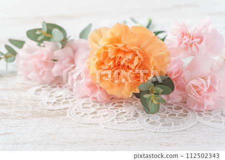 白色木質背景上的粉紅色和橙色康乃馨和桉樹排列 112502343