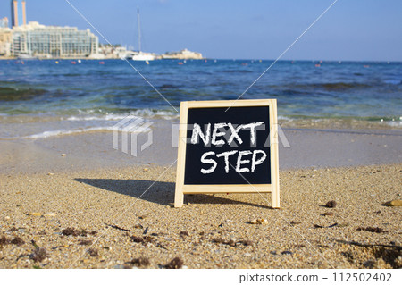 Next Step symbol. Concept words Next Step on black chalk background. Beautiful sea background. Business and Next Step concept. Copy space. 112502402