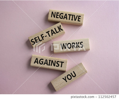 Negative self-talk works against you symbol. Concept words Negative self-talk works against you on wooden blocks. Beautiful pink background. Psychological concept. Copy space Negative self-talk works against you symbol. Concept words Negative self-talk works against you on wooden blocks. Beautiful pink background. Psychological concept. Copy space 112502457
