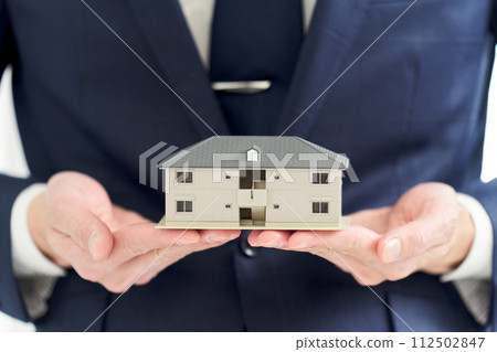 Businessman's hand holding a model of an apartment Businessman's hand holding a model of an apartment 112502847