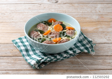 Italian Wedding Soup with meatballs and spinach on wooden table Italian Wedding Soup with meatballs and spinach on wooden table 112503202