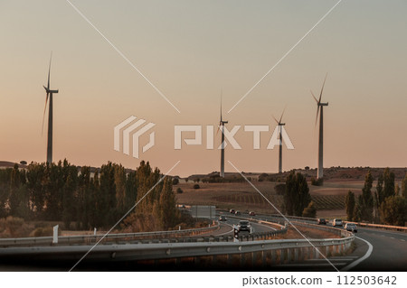 Sky high wind turbines line the highway, blending nature with infrastructure 112503642