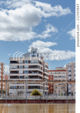Cityscape with river, buildings in background under a cumulusfilled sky Cityscape with river, buildings in background under a cumulusfilled sky 112503647