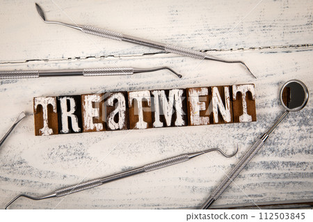 TREATMENT Concept. Alphabet blocks and dental tools on a white wooden background TREATMENT Concept. Alphabet blocks and dental tools on a white wooden background 112503845