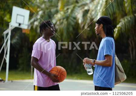 Smiling Black men talking on outdoor streetball court Smiling Black men talking on outdoor streetball court 112506205