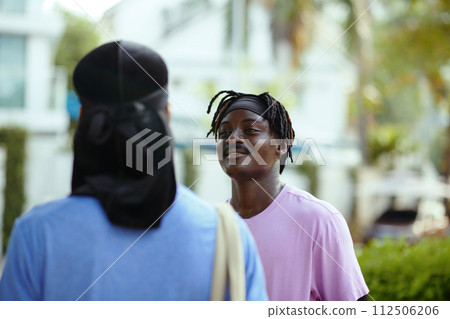 Smiling Black man talking to friend before game of basketball 112506206