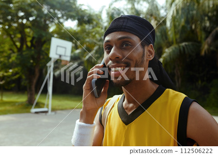 Portrait of smiling Black man calling friend, inviting him to play streetball Portrait of smiling Black man calling friend, inviting him to play streetball 112506222