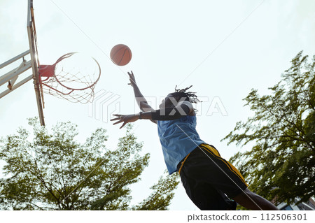 Player throwing ball in basket when playing outdoors Player throwing ball in basket when playing outdoors 112506301