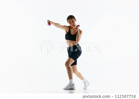 Young woman with slim sportive body training, doing jab exercises with dumbbells isolated over white studio background Young woman with slim sportive body training, doing jab exercises with dumbbells isolated over white studio background 112507758