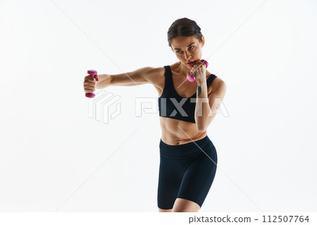 Young woman with muscular body training, doing exercises with dumbbells isolated over white studio background Young woman with muscular body training, doing exercises with dumbbells isolated over white studio background 112507764