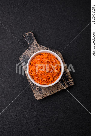 Tasty spicy Korean carrot with spices and herbs on a dark concrete background 112508295