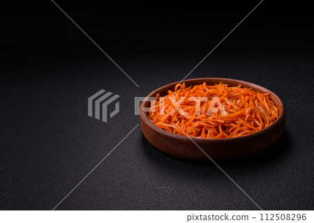 Tasty spicy Korean carrot with spices and herbs on a dark concrete background Tasty spicy Korean carrot with spices and herbs on a dark concrete background 112508296