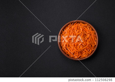 Tasty spicy Korean carrot with spices and herbs on a dark concrete background Tasty spicy Korean carrot with spices and herbs on a dark concrete background 112508298