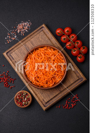 Tasty spicy Korean carrot with spices and herbs on a dark concrete background 112508310