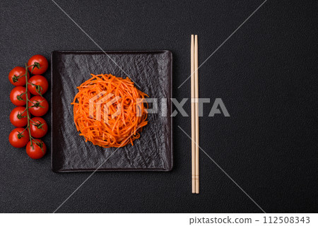 Tasty spicy Korean carrot with spices and herbs on a dark concrete background 112508343