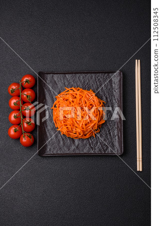 Tasty spicy Korean carrot with spices and herbs on a dark concrete background Tasty spicy Korean carrot with spices and herbs on a dark concrete background 112508345