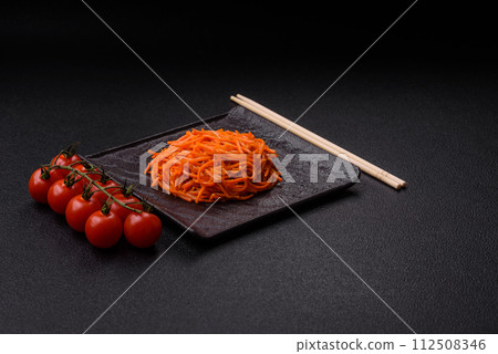 Tasty spicy Korean carrot with spices and herbs on a dark concrete background Tasty spicy Korean carrot with spices and herbs on a dark concrete background 112508346