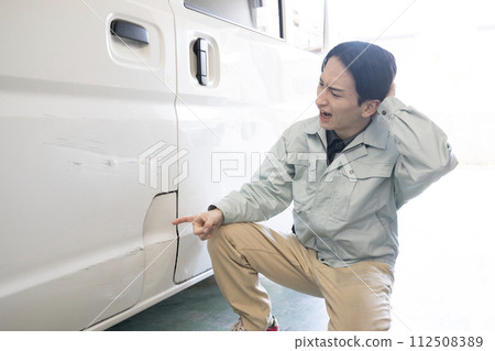 一名男子抱著頭指著自己車上的刮痕 一名男子抱著頭指著自己車上的刮痕 112508389