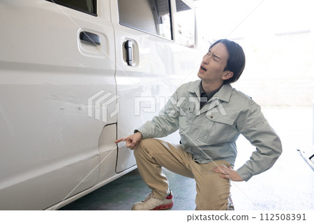 一個男人坐在汽車旁邊,抱著頭 一個男人坐在汽車旁邊,抱著頭 112508391