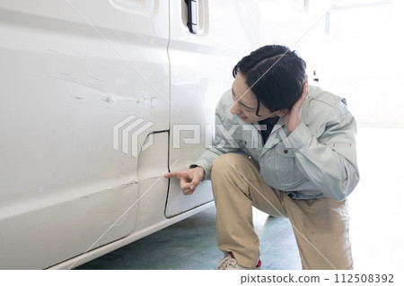 A worker giving an estimate for repairing a damaged car A worker giving an estimate for repairing a damaged car 112508392