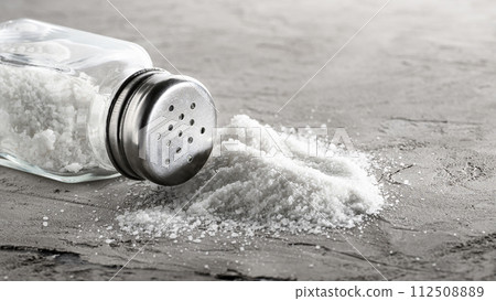 Salt glass jar and pile of spilled salt on a concrete plate Salt glass jar and pile of spilled salt on a concrete plate 112508889