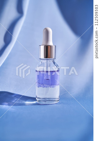 Two-component facial serum on a blue silk background. 112509383
