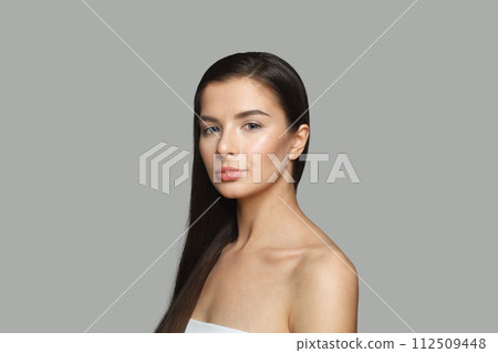 Stylish female model with long perfect hair and clean skin posing on gray studio wall background 112509448
