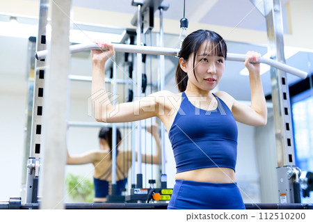 Woman working out at the gym, lat pulldown, female muscle training, workout Woman working out at the gym, lat pulldown, female muscle training, workout 112510200