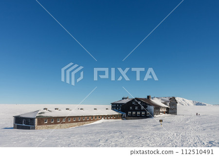 Meadow Hut , ski lodge,  krkonose mountains Czech Republic. Winter morning, on background  Snezka,  mountain on the border between Czech Republic and Poland. 112510491