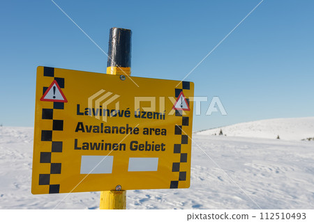 A sign warning of the avalanche area, white elbe valley, krkonose mountains, winter day. Avalanche area warning sign in czech, english and german language. A sign warning of the avalanche area, white elbe valley, krkonose mountains, winter day. Avalanche area warning sign in czech, english and german language. 112510493