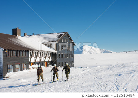 Three man on skies, ski touring in krkonose mountains, path in front of  Meadow Hut. Winter morning, on background  Snezka, mountain on the border between Czech Republic and Poland. 112510494
