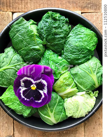 Cabbage rolls in green fresh cabbage lie in a frying pan before frying. AI-generated item 112510800