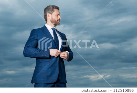 Professional man sky background. Grizzled man buttoning suit. Serious man looking aside, copy space 112510896