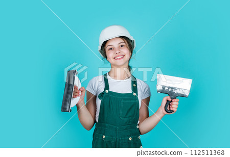 teen girl plasterer in protective helmet use spatula, plastering 112511368