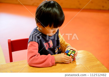 Boy playing with rubik's cube Boy playing with rubik's cube 112512482