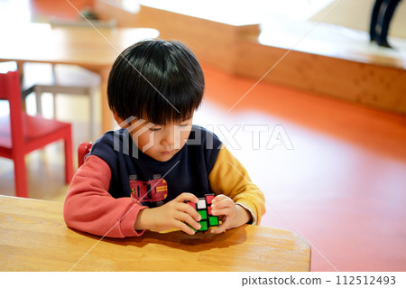 Boy playing with rubik's cube 112512493
