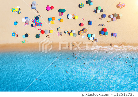 Aerial view of umbrellas on white sandy beach, blue sea at sunset 112512723