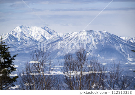 A view of the Northern Alps from Mt. Yakebita in Shiga Kogen, looking towards Suzaka City and Nagano City. 112513338