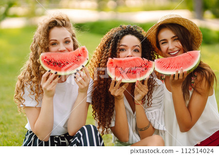 Three young woman have fun together and eating watermelon in hot summer day. Three young woman have fun together and eating watermelon in hot summer day. 112514024