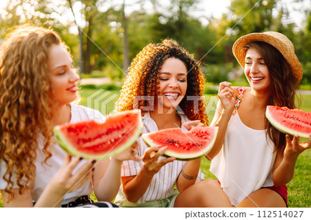 Three young woman have fun together and eating watermelon in hot summer day. 112514027