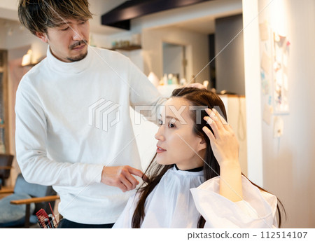 A woman getting her hair cut at a beauty salon A woman getting her hair cut at a beauty salon 112514107