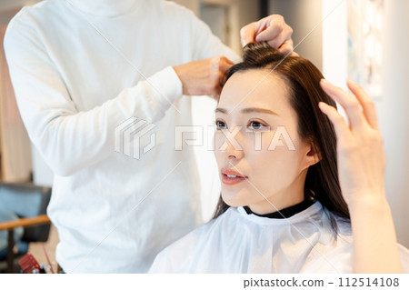 A woman getting her hair cut at a beauty salon A woman getting her hair cut at a beauty salon 112514108