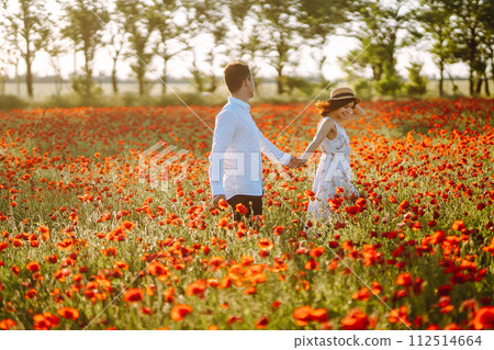 Loving couple in the poppy field at sunset. Enjoying time together. love and lifestyle. 112514664